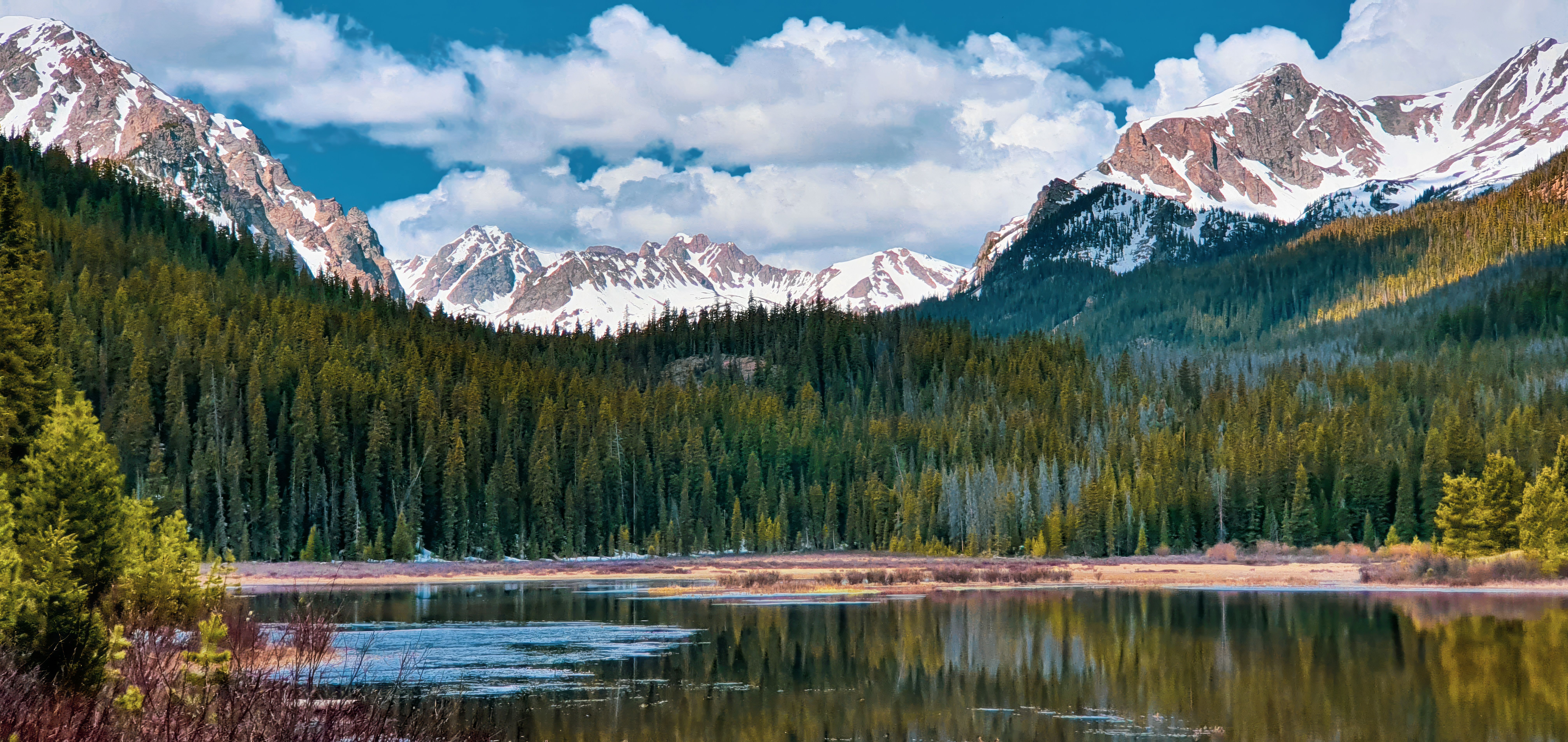 Colorful Colorado mountain lake surrounded by pine forest and peaks